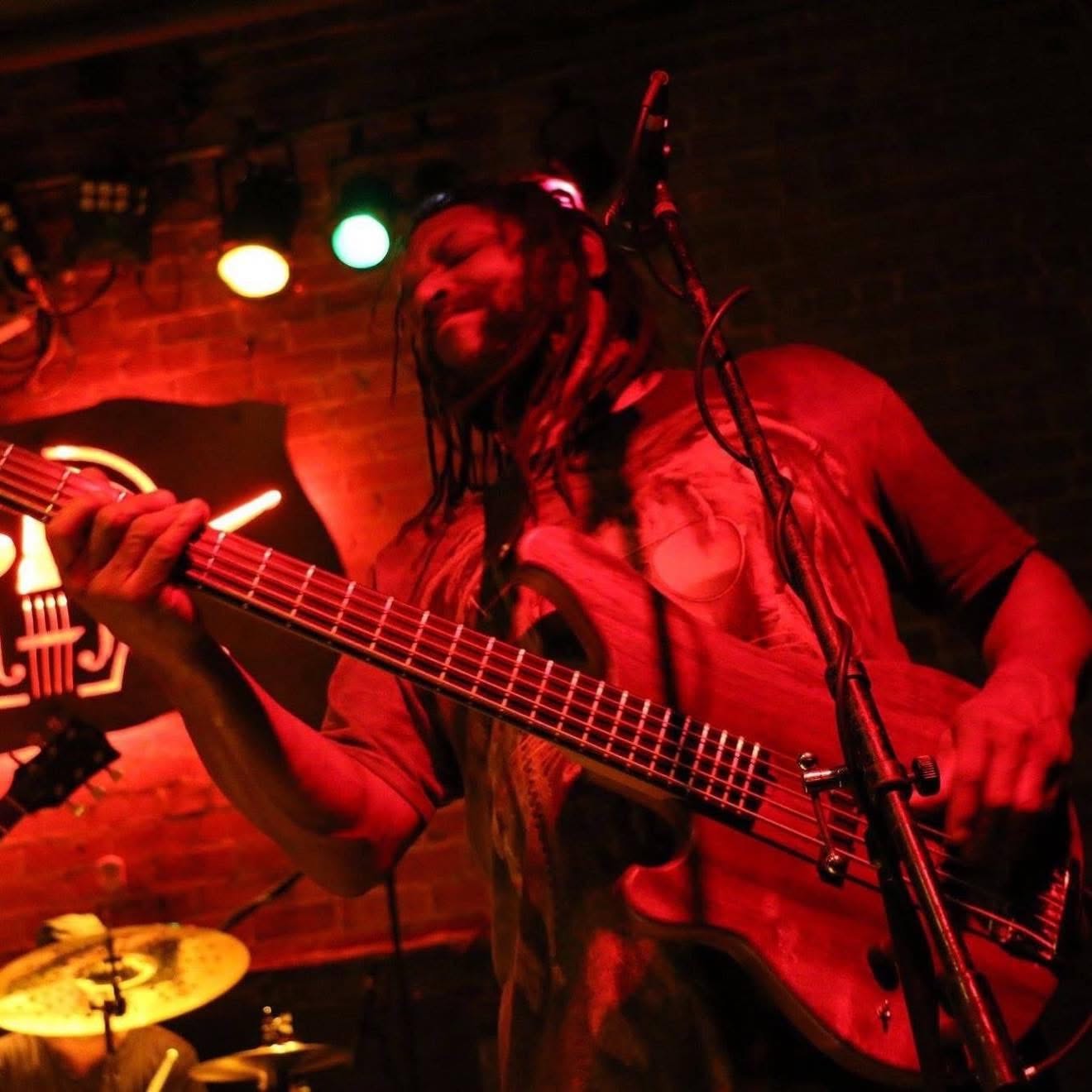 Amochip Dabney playing bass under red stage lighting